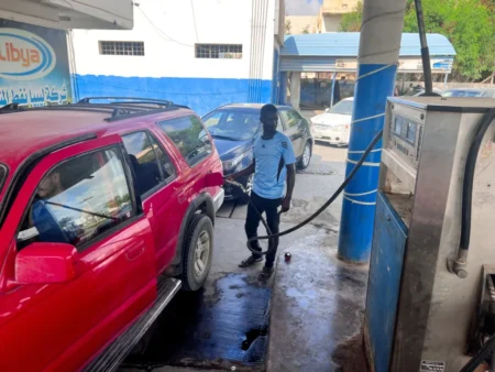 A gas station attendant pumps fuel into a red SUV at a service station in Libya, illustrating the domestic energy infrastructure amid debates over a national oil windfall.