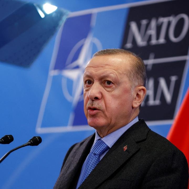 Turkey’s Limited Role in the Iran War Turkish President Recep Tayyip Erdogan stands before a blue NATO backdrop during an address, offering a visual focal point for analyzing Turkey's Limited Role.