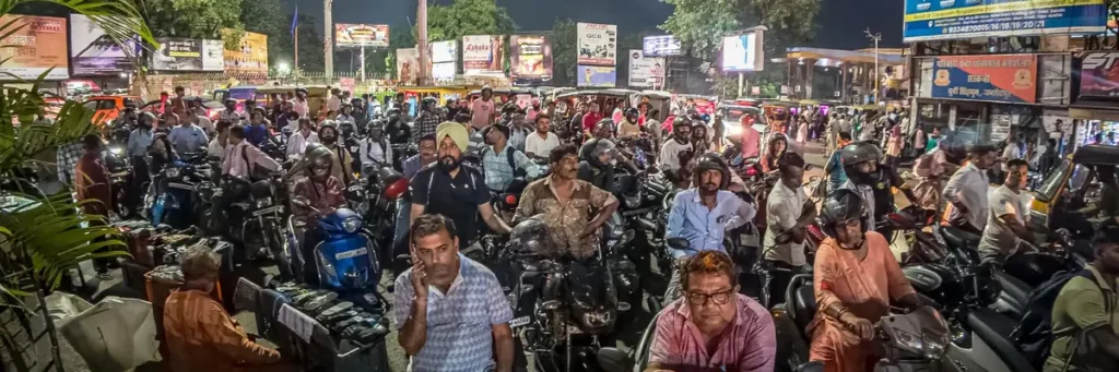 More Iran war? There goes the neighborhood, and world economy A densely packed urban street at night with commuters on motorcycles illustrates the vulnerability of global developing economies to the market shocks of More Iran war.