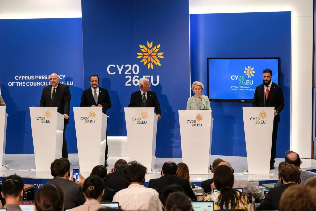Syrian President Ahmed al-Sharaa speaks at a podium alongside European Union heads of state during an international press conference, illustrating regional diplomatic involvement regarding Iran war's aftermath.