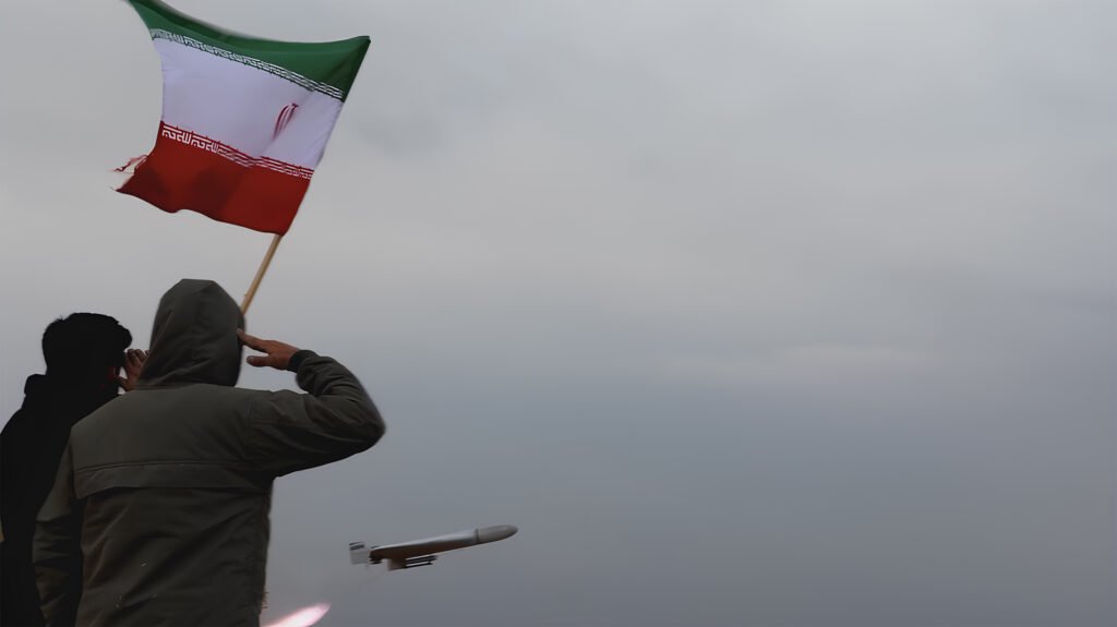 A person in a hooded jacket saluting the Iranian flag against an overcast sky as a drone launches in the foreground, representing the military leverage and defense capabilities influencing the Iran-US Negotiations and the 2026 truce.