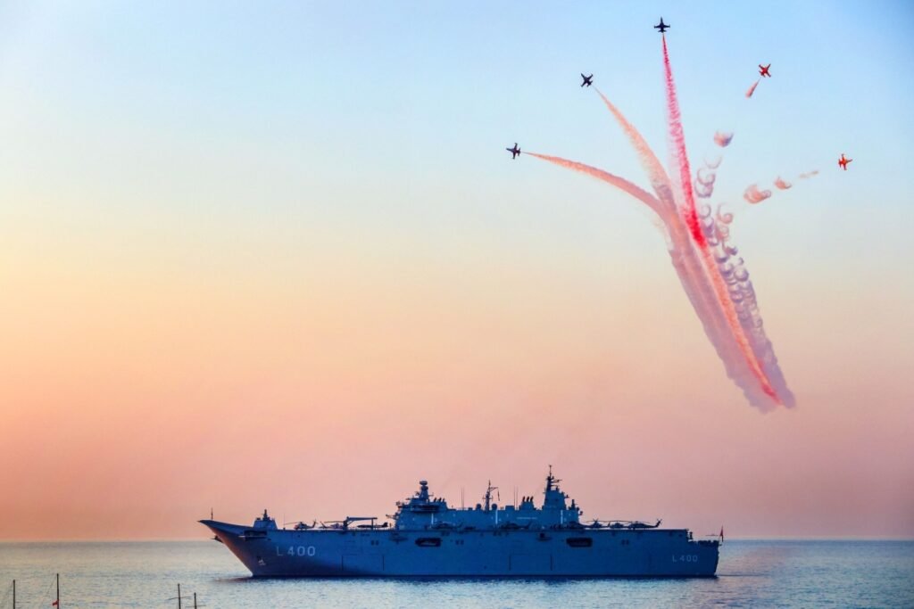 A low-angle shot of Turkish F-16 fighter jets soaring in formation over a naval warship in the waters of Kyrenia, Northern Cyprus, showcasing the integrated air and sea power central to the Türkiye Defense Strategy and Ankara's regional influence.