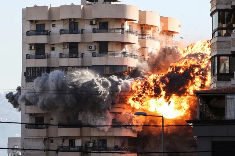 Curbing Iran Means an Israel Unfettered in Lebanon A massive fire explosion with bright orange flames and dense gray smoke erupts from the side of a residential apartment building, demonstrating the severe kinetic impacts associated with an Israel unfettered.