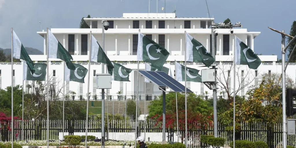 Rows of Pakistani flags fluttering in front of the Parliament House (Aiwan-e-Sadr) in Islamabad, representing the governmental and legislative framework that governs Pakistan Iran Trade Routes and bilateral economic policies.