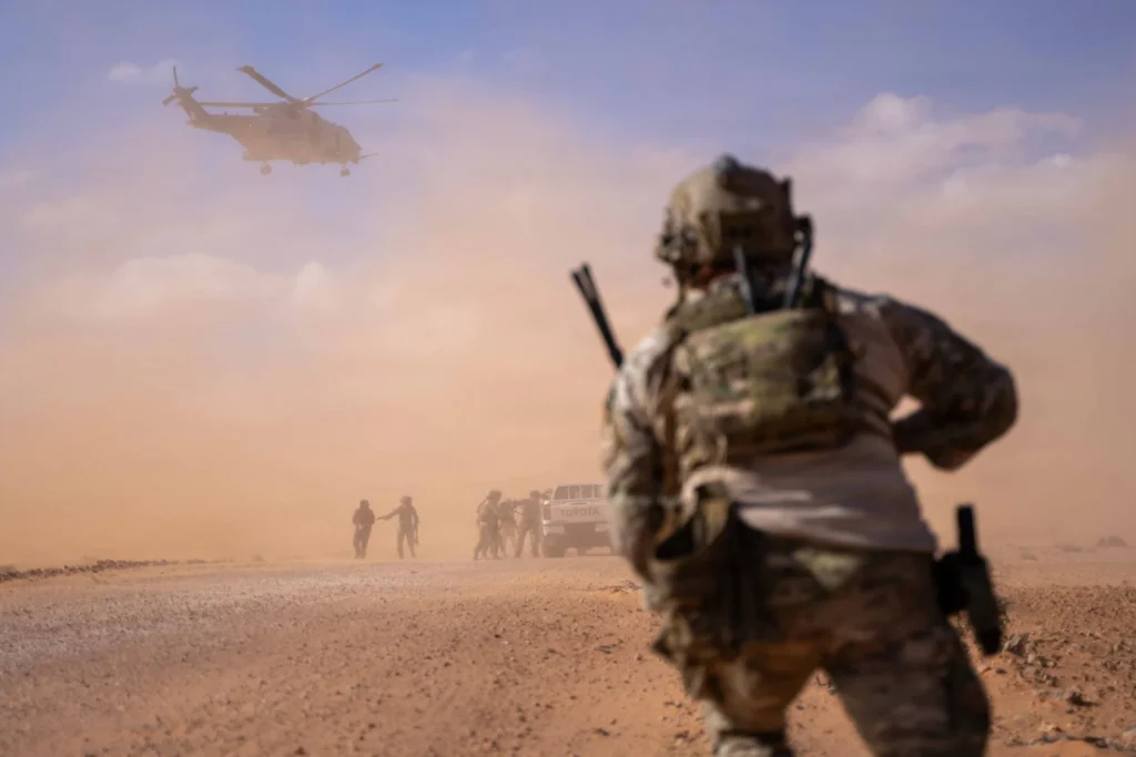 A US service member runs through a dust cloud toward a military helicopter during tactical vehicle interdiction maneuvers at Flintlock, highlighting operational frameworks shaping the future of US counterterrorism.