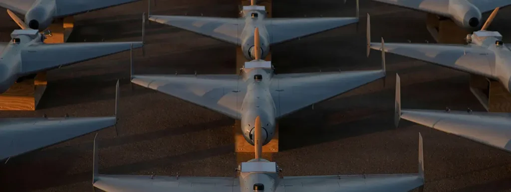 Rows of delta-wing loitering munitions, specifically Shahed-style drones, arranged on the ground to showcase the scale of aerial technology and its pivotal role in the modern landscape of The Iran War.