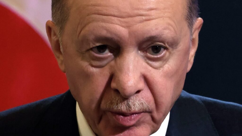 Close-up portrait of Turkish President Recep Tayyip Erdoğan with a stern expression, symbolizing the political leadership and regional influence associated with the SADAT paramilitary instrument expansion.