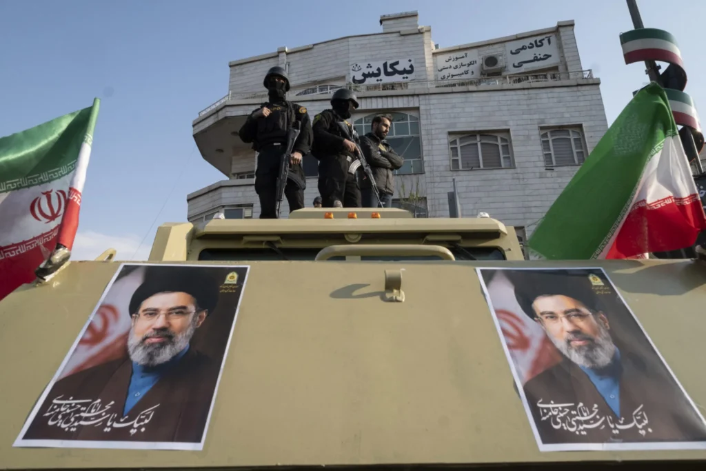 Tehran wants to end the war—but not at any price Armed members of Iran's Special Police Forces stand guard on an armored military vehicle featuring two portraits of Ayatollah Mojtaba Khamenei in Tehran, reflecting the internal dynamic as Tehran wants to end the war.