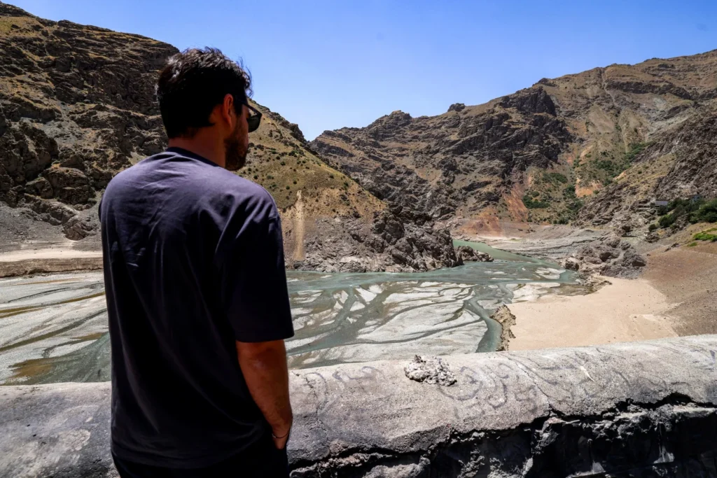 Water, not oil, is the Middle East’s most precious commodity A man from behind stands on a concrete edge overlooking a significantly low water inlet of the Karaj river upstream from the Amir Kabir Dam, surrounded by arid mountain slopes to underscore why water not oil is becoming the region's critical focus.