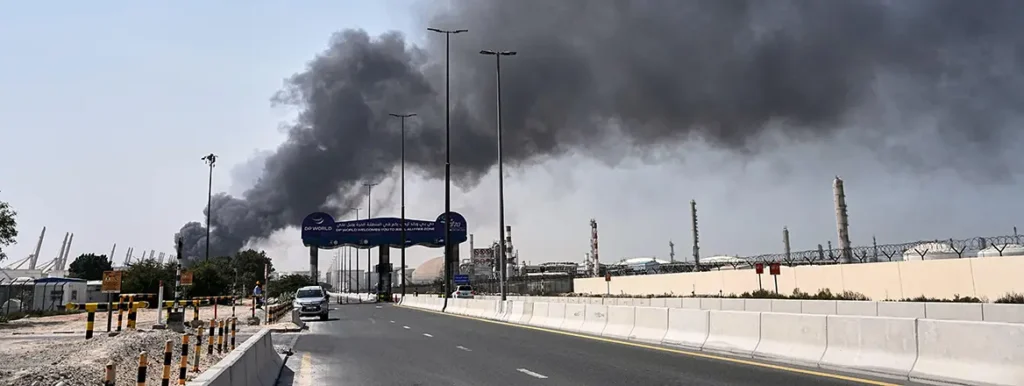 Plume of dark smoke billowing from an industrial port facility in Dubai after an aerial strike, demonstrating the regional threats that drive UAE-Israel Security Ties.