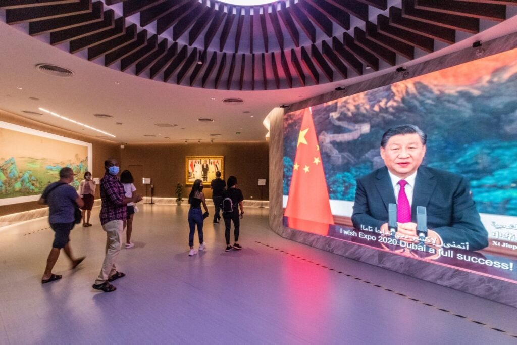 Visitors walk through the China pavilion at Expo 2020 in Dubai, where a large curved screen displays Chinese President Xi Jinping, reflecting shifting public sentiments across the Arab World.