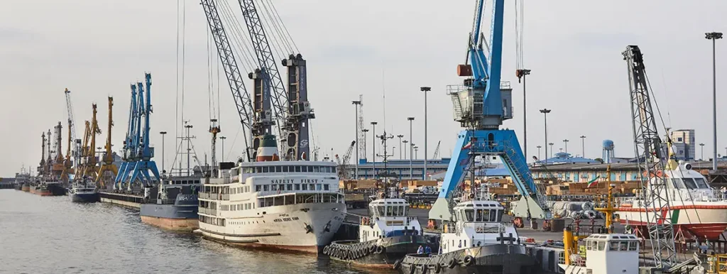 Commercial port terminal with cargo ships and cranes, illustrating the logistical challenges for Russia’s military supply chains during The Iran-Israel War.