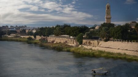 Scenic view of a historic Iraqi riverfront with a clock tower and traditional boat, illustrating the cultural backdrop against which Iraq corruption Ali al-Zaidi fails the nation and undermines national heritage.
