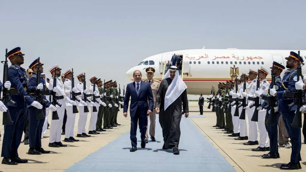Egyptian President Abdel Fattah el-Sisi and UAE President Sheikh Mohamed bin Zayed Al Nahyan walk along a red carpet on an airport tarmac lined with a military honor guard near an official aircraft, symbolizing regional alignment and the shifting Strategic Balance.
