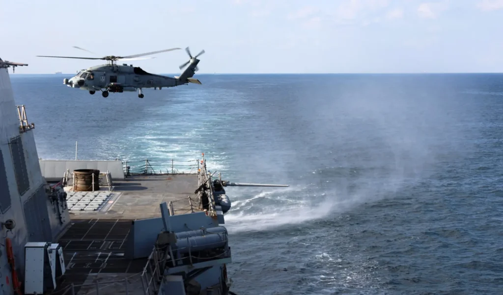 Demining the Strait of Hormuz: Q&A with Scott Savitz An MH-60R Sea Hawk helicopter hovers near the flight deck of the Arleigh Burke-class guided-missile destroyer USS Roosevelt during a deployment focused on tracking maritime threats and Demining the Strait of Hormuz.
