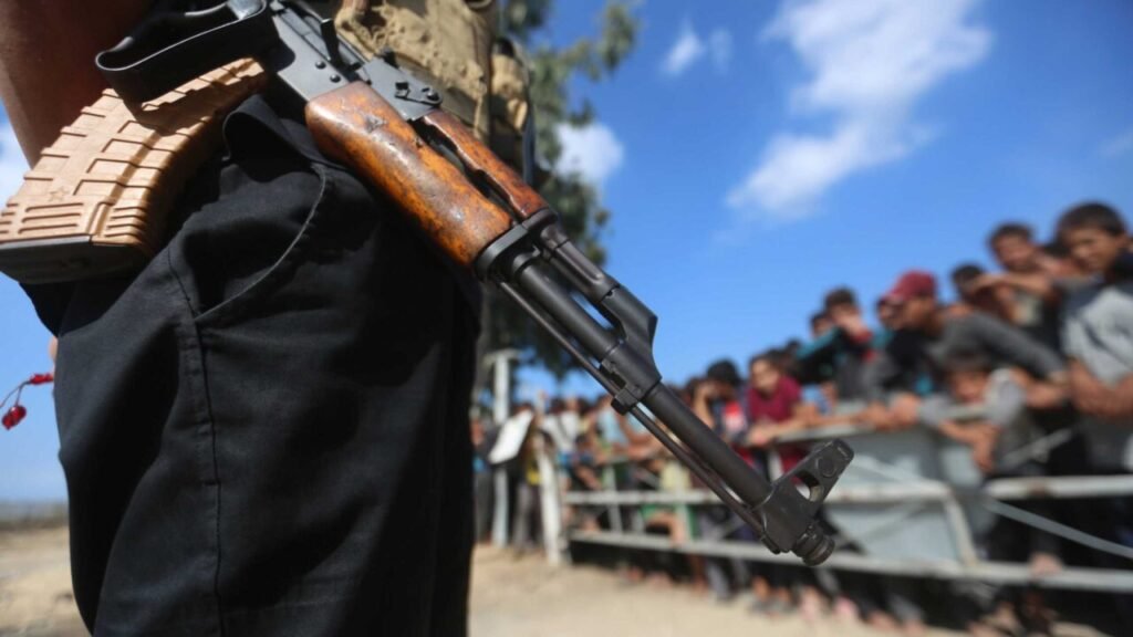 A close-up profile view of an AK-47 assault rifle held by an armed individual in black clothing, framing the complex security negotiations surrounding the disarmament of Hamas's weapons to rescue the Gaza ceasefire.