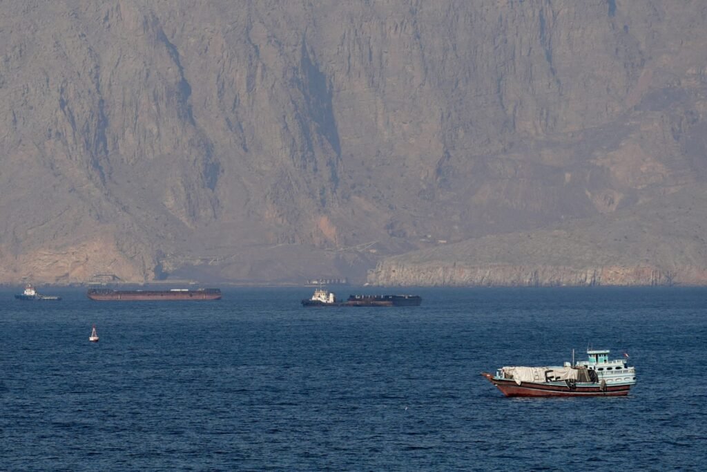 The Limitations of Hard Power in Iran Large commercial ships and tankers navigate the deep blue waters of the Strait of Hormuz off the rocky coastline of Musandam, Oman, visually illustrating the critical maritime chokepoints that highlight the limitations of hard power.