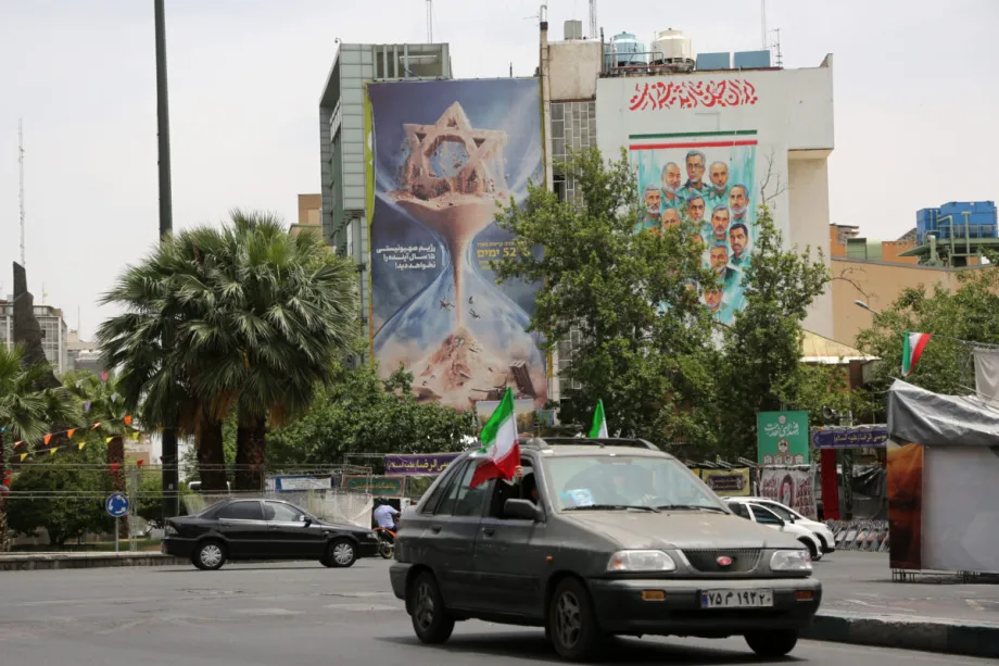Could Iran’s new air defence system be a game changer? A street view of Palestine Square in Tehran showing cars driving past a large anti-Israel billboard with an hourglass graphic alongside a mural of military figures, capturing the deterrence messaging linked to Iran's new air defence.