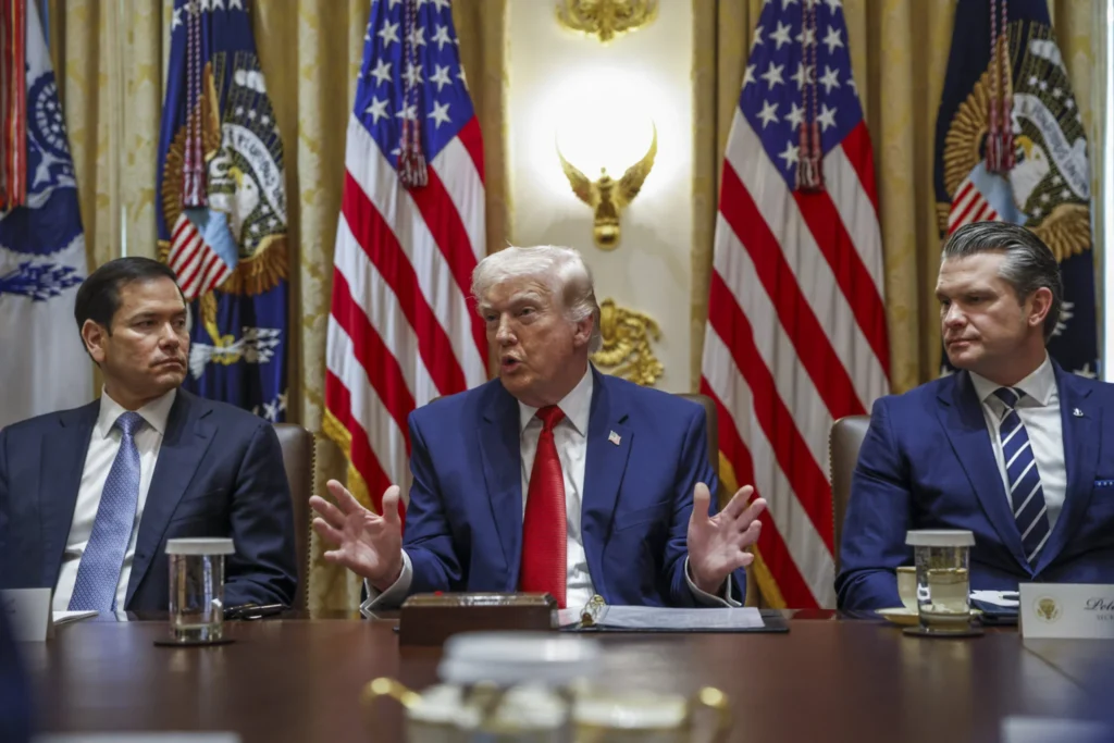 ليس ‘اتفاقًا’. لكن مذكرة ترامب مع إيران يمكن أن تكون بداية لشيء أكبر Donald Trump gestures broadly with his hands during a high-level meeting flanked by Marco Rubio and Pete Hegseth in front of American flags, providing context to the ongoing diplomatic talks surrounding Trump's memorandum with Iran.