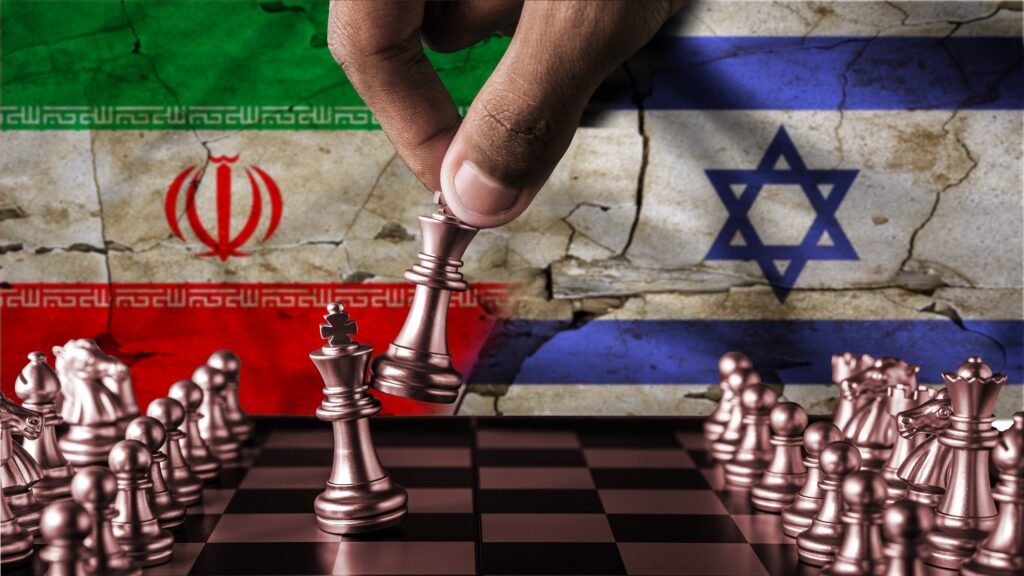 A hand moving a metallic chess king piece to topple another king on a chessboard, set against a cracked wall background depicting the national flags of Iran and Israel, capturing the intense strategic rivalry and brinkmanship underlying the assertion that Iran Thinks Time Is Its Best Weapon.