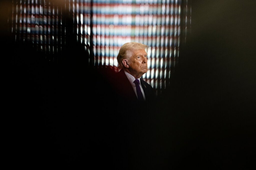 A silhouette and side profile of U.S. President Donald Trump set against a dimly lit backdrop with vertical stripes of light, captured in a moment of reflection to illustrate the strategic policy challenges of ending the Iran war.