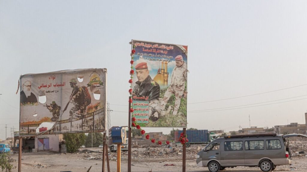 Large public posters honoring members of the Popular Mobilization Forces (PMF) stand along an urban roadside in Nasiriyah, Southern Iraq, illustrating the deep entrenched domestic influences that Iraq's leadership must navigate regarding the US-Iran needle.
