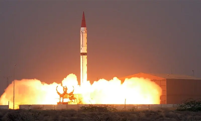 بازاندیشی در بازدارندگی، ۲۸ سال پس از چاغای A white nuclear-capable ballistic missile with a red tip launches into a dark sky amidst massive clouds of fire and smoke from a desert facility, providing a historical context to the ongoing strategic shift toward reimagining deterrence.