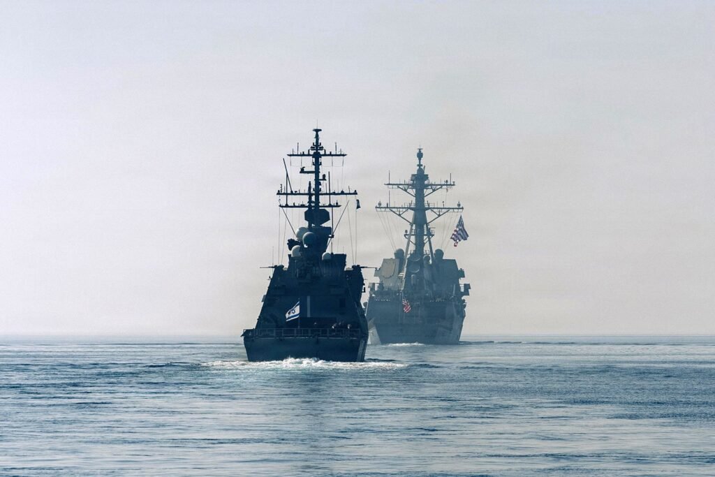 Two naval warships, including an Israeli vessel and a US Navy destroyer, sailing through open waters to counter the Red Sea's Threat to global shipping lanes.