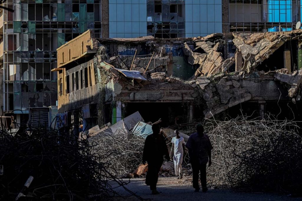با نزدیک شدن شاخ آفریقا به نقطه جوش، زمان دیپلماسی فوری فرارسیده است Sudanese men walk through a street filled with rubble past destroyed buildings in Khartoum, illustrating the severe humanitarian impact of regional instability across the Horn of Africa.
