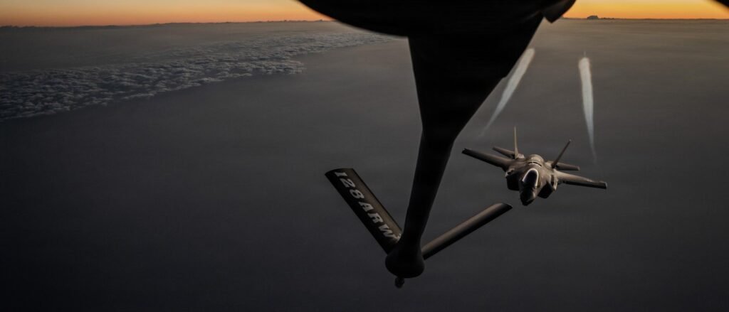 An F-35 fighter jet performs mid-air refueling with a tanker boom, capturing a high-altitude maneuver that highlights the logistical complexities and the massive Epic Fury Cost of sustained air operations.