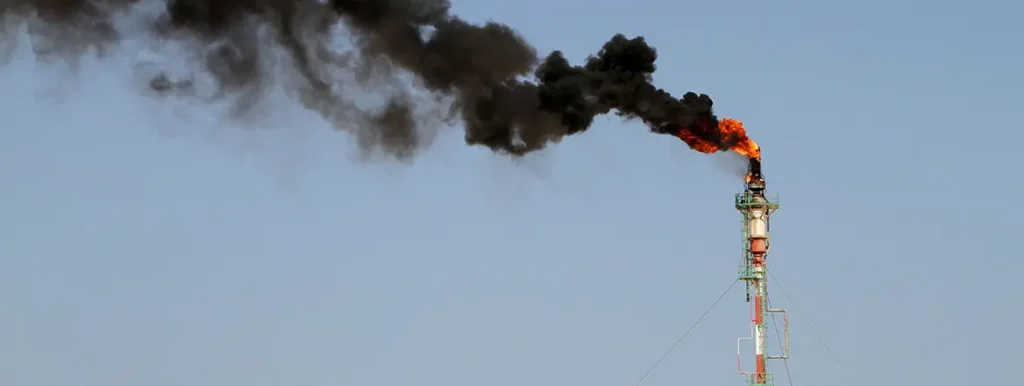 North Africa’s Flaring Problem is Europe’s Gas Opportunity A tall industrial flare stack emitting a bright orange flame and a thick plume of black smoke against a clear sky, illustrating energy flaring related to Europe's Gas Opportunity.