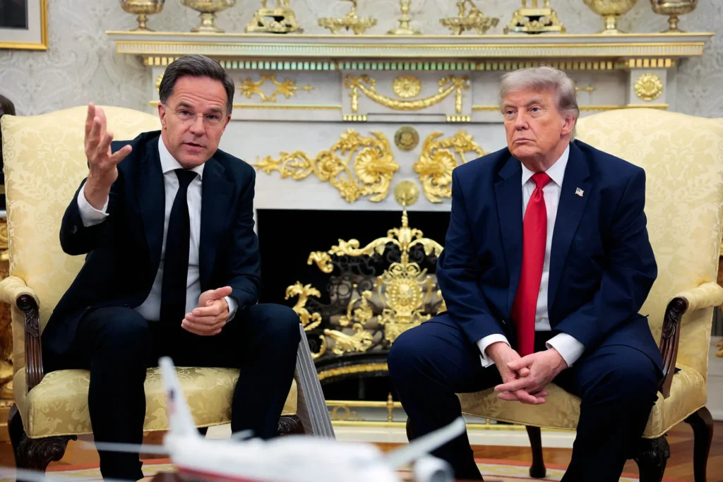 NATO Secretary General Mark Rutte speaks and gestures with his hand while seated in an ornate room alongside Donald Trump in a dark suit and red tie, capturing trans-Atlantic diplomatic dynamics related to an accelerating U.S. Decoupling.