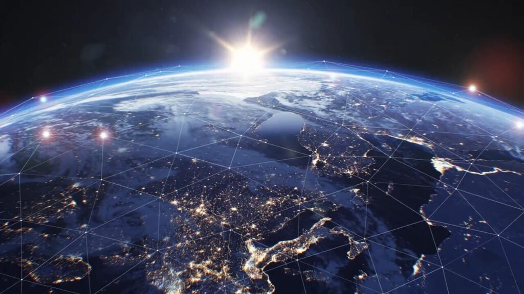 A satellite view of Earth from space showing illuminated city lights and a digital network grid overlaid across continents with the sun rising over the horizon, highlighting global connectivity linked to Iran War Maritime Security.