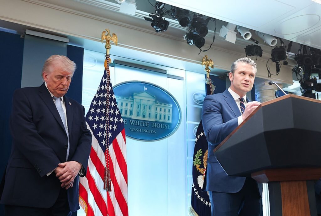 As Iran war escalates, U.S. is fighting from a weakened position President Donald Trump standing quietly beside Defense Secretary Pete Hegseth as he speaks at the White House podium, outlining defense strategy as the Iran war escalates.