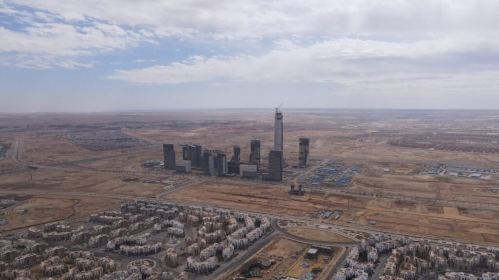 An aerial drone view looking over the New Administrative Capital under construction with high-rise buildings and modern skyscrapers rising from the desert landscape outside Cairo, Egypt, reflecting regional infrastructure and Economic Development.
