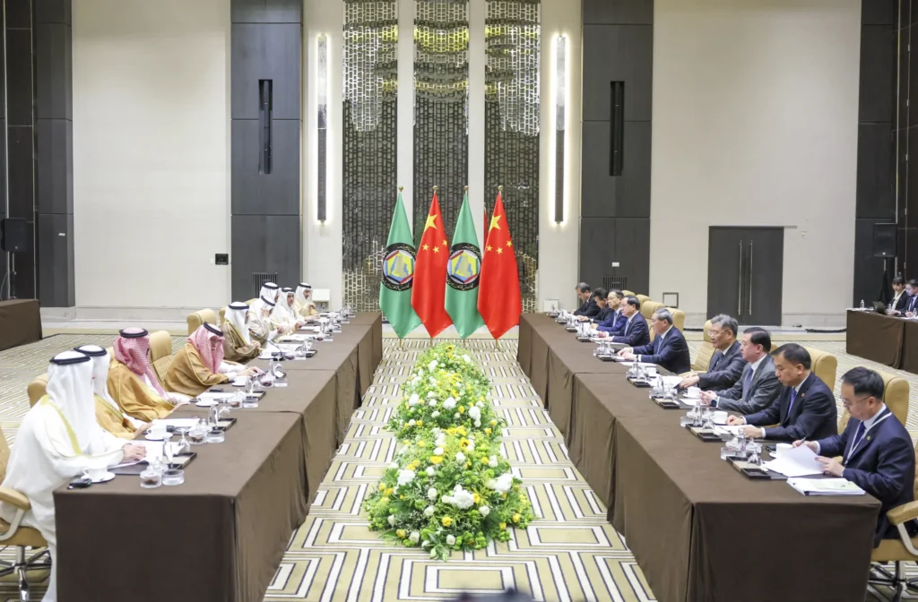 China-GCC Relations in an Emerging Multipolar Order Chinese delegates in dark suits seated opposite Gulf Cooperation Council officials in traditional attire across a long summit table flanked by Chinese and GCC flags, illustrating high-level bilateral talks shaping China-GCC Relations.