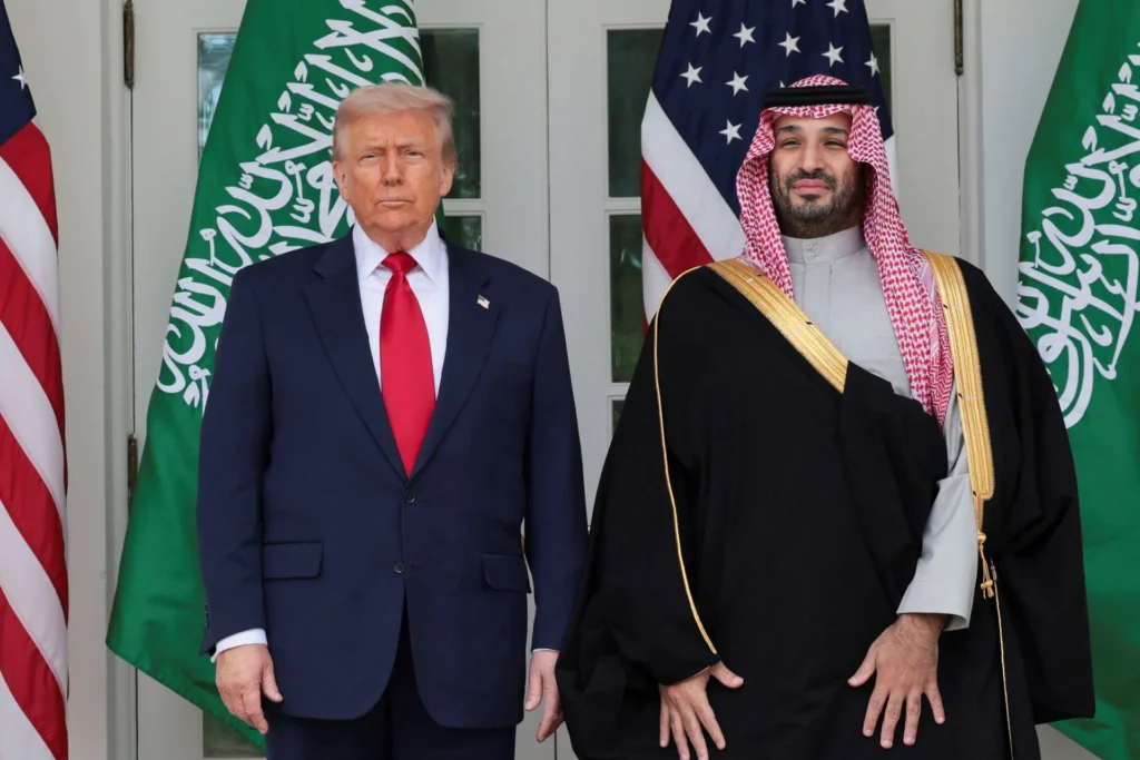 Donald Trump and Saudi Crown Prince Mohammed bin Salman standing side by side in front of American and Saudi Arabian flags, highlighting bilateral diplomatic negotiations surrounding the Saudi Nuclear Deal.
