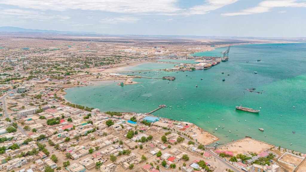 شناسایی سومالیلند: چرا ایالات متحده باید اتیوپی را به اقدام تشویق کند An aerial high-angle view of the Berbera Port stretching into the turquoise waters of the Gulf of Aden with docked ships and coastal infrastructure, highlighting maritime trade assets linked to Somaliland Recognition.