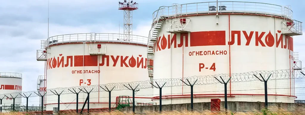 آینده تحریمهای روسیه پس از بحران هرمز A close-up view of large white oil storage tanks at the Kaliningrad refinery featuring red Russian text and labels P-3 and P-4, enclosed by a security fence with barbed wire under a cloudy sky, illustrating energy sector vulnerabilities under Russian Sanctions.