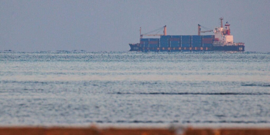حصار الحوثيين للبحر الأحمر: هل سيتم الدفاع عن الأمن البحري الجماعي أم سيتفكك؟ A large commercial container ship sailing across open waters near the horizon toward the Bab-el-Mandeb strait, illustrating global shipping challenges linked to the Red Sea blockade.