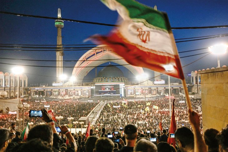 ایرانیها برای از سرگیری جنگ اسرائیل و ایران قبل از اکتبر آماده میشوند Mourners waving an Iranian flag during a massive funeral gathering at Tehran's Grand Mosalla following high-level regional strikes, highlighting public sentiments ahead of a potential Israel Iran war restart.