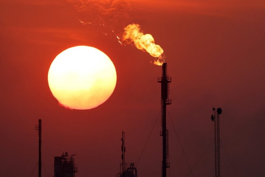 Energy in Iraq: the new front line between Washington and Tehran A bright setting sun beside a burning gas flare stack at the Daura Oil Refinery Complex in Baghdad silhouetted against a deep red sky, highlighting oil production infrastructure tied to Energy in Iraq.