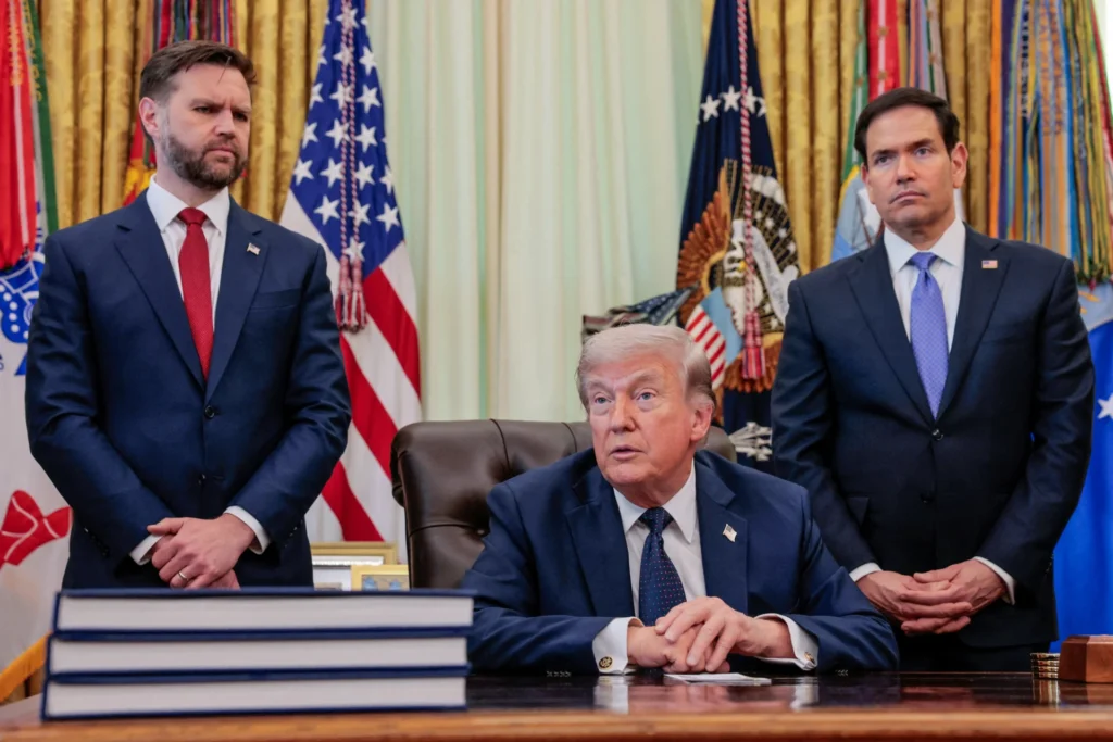 Trump’s Iran Food Deal Could Easily Become Another Oil-for-Food Scandal US President Donald Trump sits at his desk in the Oval Office with his hands clasped, flanked by Vice President JD Vance on the left and Secretary of State Marco Rubio on the right, under American flags, framing the policy discussions around the Iran food deal.