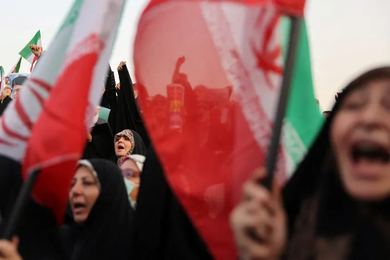 شکست آتشبس ایران هزینه توافقهای سریع را نمایان میسازد Iranian women wearing chadors wave national flags and raise their hands in unity during a public street rally, reflecting public sentiment surrounding the Iran ceasefire failure.