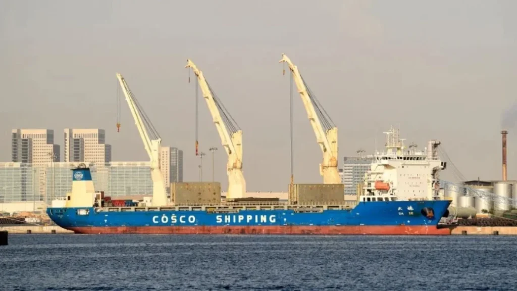 A COSCO Shipping cargo vessel docked at the port of Jebel Ali with large cranes and city buildings in the background, illustrating regional commercial corridors and the Israel Trade Hub.