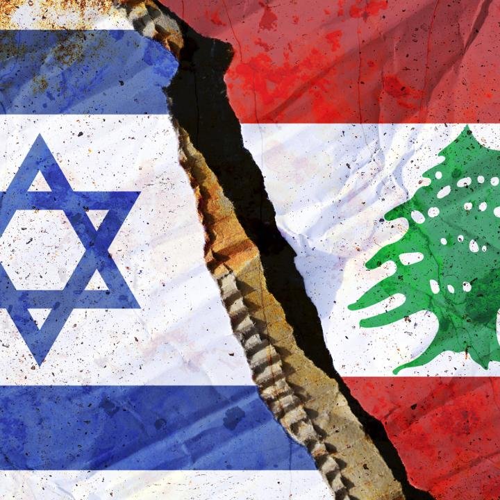 إلغاء قوانين لبنان ‘مناهضة التطبيع’: شرط أساسي للسلام A deep, jagged crack in weathered stone physically separates the national flag of Israel on the left from the national flag of Lebanon on the right, abstractly representing political divides and regional Anti-Normalization Laws.