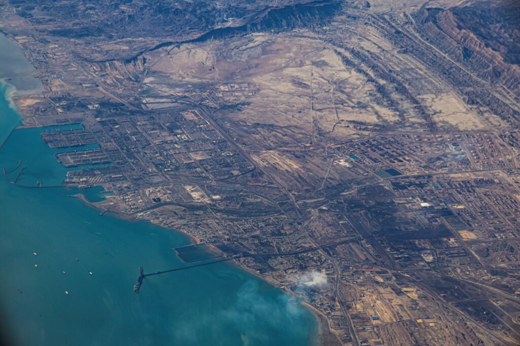 Digital Risks in the Strait of Hormuz Present New Challenges An aerial high-altitude view of the Port of Fujairah coastline and industrial maritime infrastructure along the water, highlighting critical trade and energy assets vulnerable to Digital Risks.