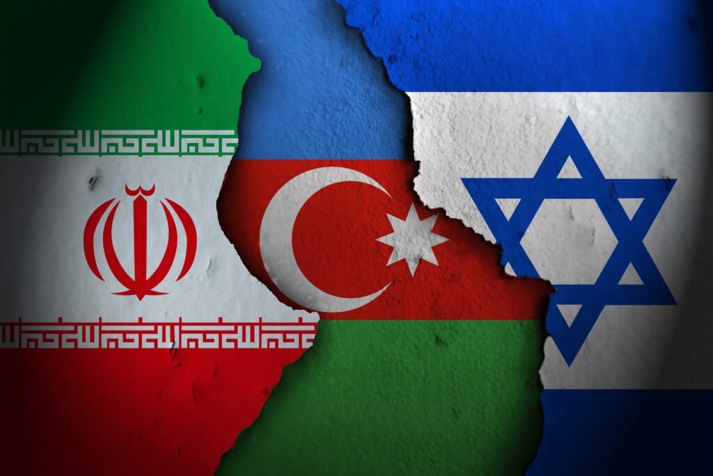 A textured wall backdrop showing the national flag of Azerbaijan positioned in the center, flanked by deep cracks separating it from the flag of Iran on the left and the flag of Israel on the right, visually representing Azerbaijan's Delicate Balance.