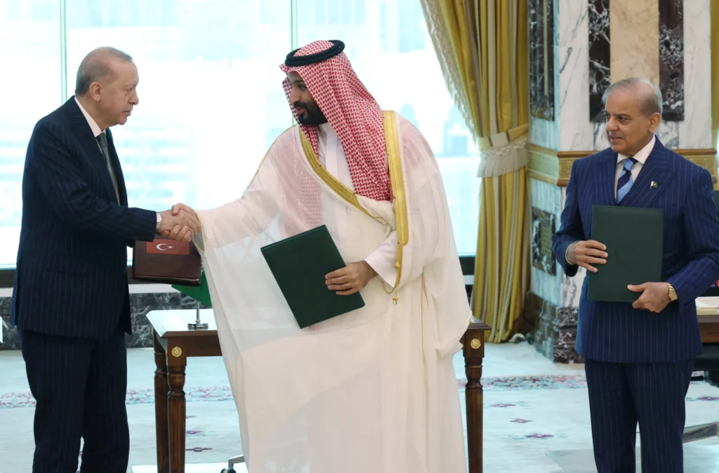 Turkish President Tayyip Erdogan shaking hands with Saudi Crown Prince Mohammed bin Salman alongside Pakistani Prime Minister Shehbaz Sharif after signing the historic Mecca Defense Pact.