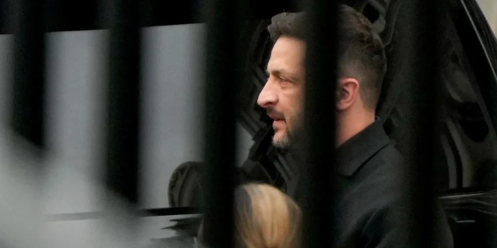 Ukrainian President Volodymyr Zelensky seen in profile through dark metal bars, reflecting the high-stakes political maneuvers behind Zelensky's dangerous gambit to merge the Iran and Ukraine wars.